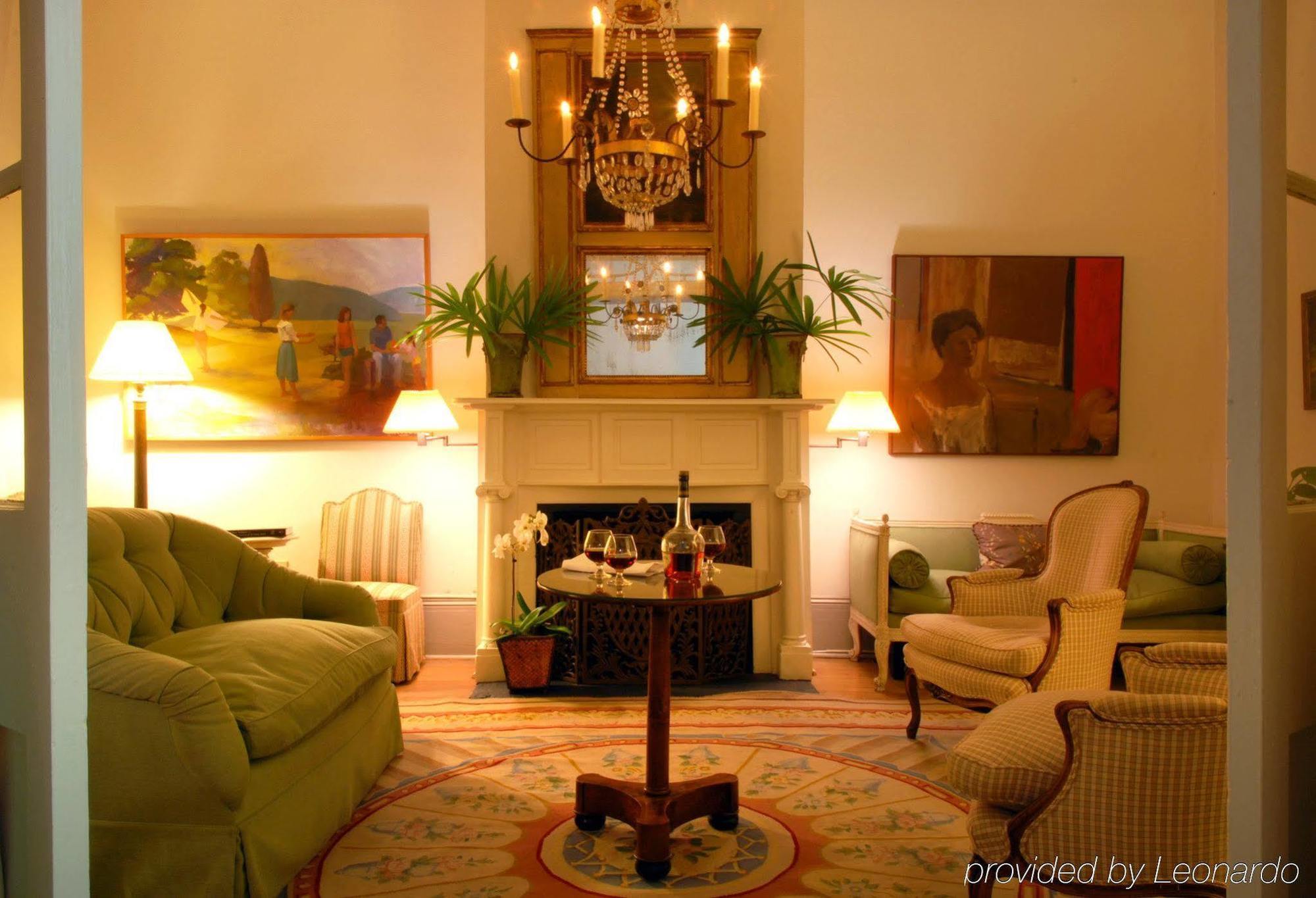 A warmly lit hotel lobby with a fireplace, chandelier, and comfortable seating area.